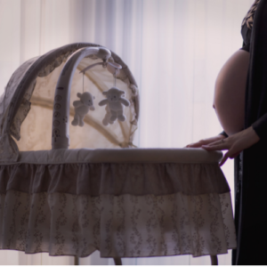 pregnant mom standing next to cot